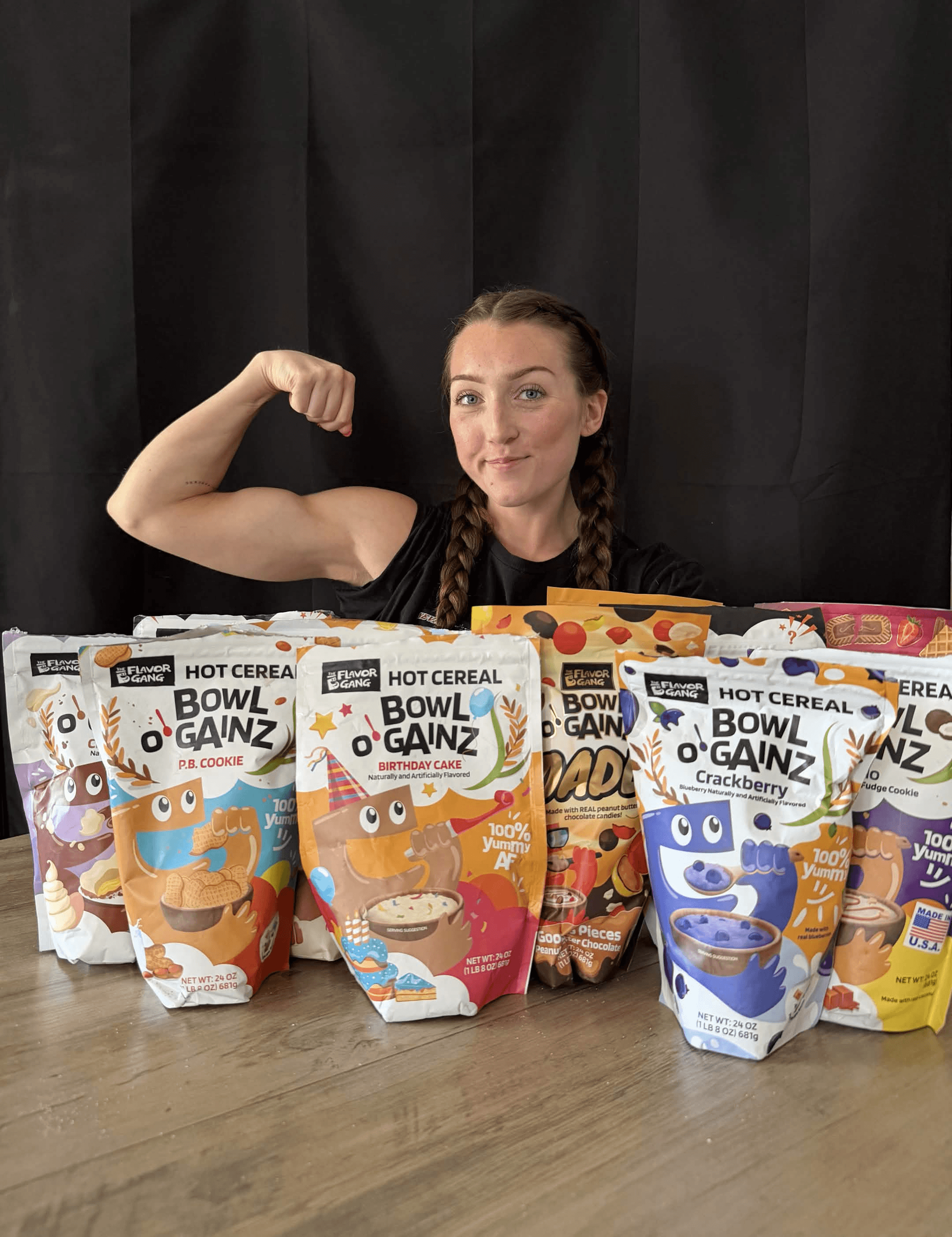 Woman flexing her bicep behind The Flavor Gang Bowl O' Gainz high-protein cream of rice hot cereal in six dessert flavors