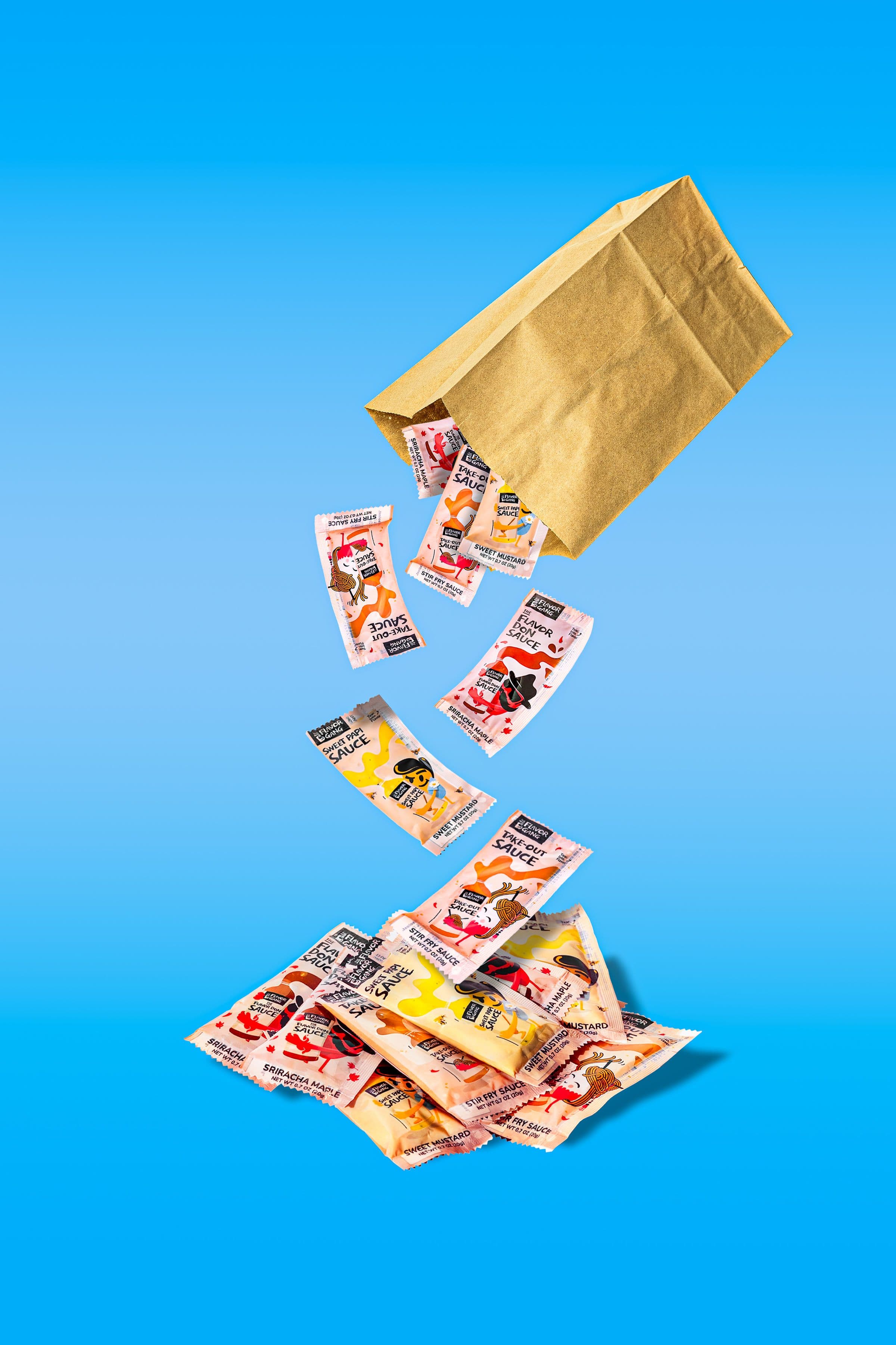 The Flavor Gang Lil Saucey single-serve packets falling from a kraft bag — Flavor Don, Sweet Papi, and Take-Out sauce